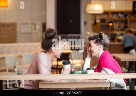 Weibliche fröhliche Mitarbeiter zusammen zu Mittag essen, in der Mall, Geselligkeit und tratschen über Kollegen Stockfoto
