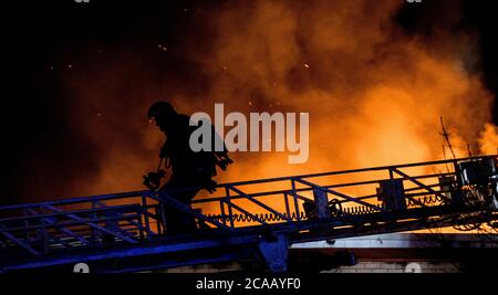 Feuerwehrmann im Schatten Schlachthaus Feuer von Leiter. Stockfoto