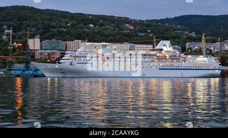 Nachtansicht von Cruise Liner Pacific Venus mit beleuchteten, Lichter im Bullauge und Reflexion im Wasser verankert am Pier im kommerziellen Pazifik Hafen Stockfoto