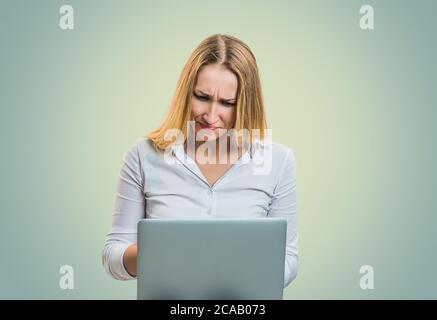 Moderne blonde Frau finster in Missverständnisse bei der Verwendung von Laptops auf grauem Hintergrund Stockfoto