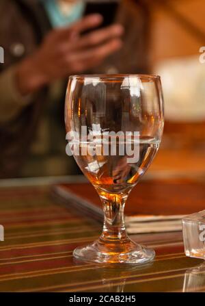 Vertikale Aufnahme eines halb vollen Glases mit Wasser auf einem Unscharfer Hintergrund Stockfoto