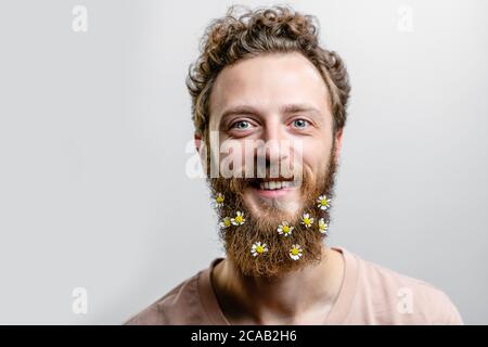 Porträt von lächelnd positive Erwachsene Nerd, biologische Wissenschaftler mit kleinen Gänseblümchen im Bart drückt Sympathie. Gutherzig freundlich schön Hippie Shows k Stockfoto