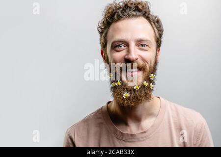 Angenehm, gutherzig glücklich Hipster Kerl lächelt an der Kamera, drückt positive Emotionen Sympathie und große Liebe. Fröhlicher romantischer Blumenmann mit dai Stockfoto