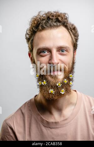 Angenehm, gutherzig glücklich Hipster Kerl lächelt an der Kamera, drückt positive Emotionen Sympathie und große Liebe. Fröhlicher romantischer Blumenmann mit dai Stockfoto