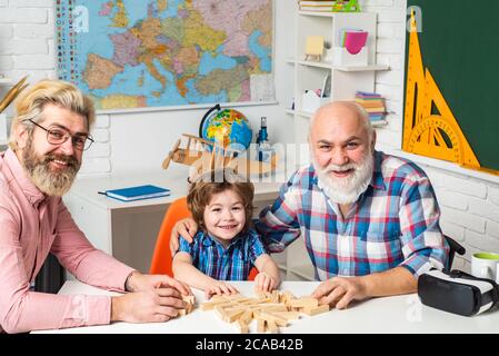 Männlich Multi Generation Portrait. Älterer Mann spielt seinen Enkel und Sohn. Großvater Vater und Sohn spielen drinnen. Stockfoto