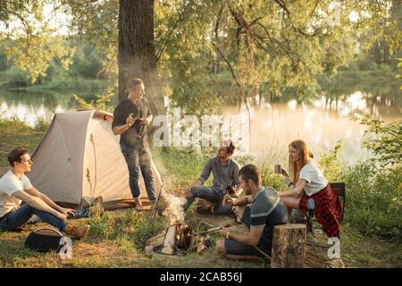 Kollegen sind um das Lagerfeuer versammelt und ruhen nach harter Arbeit Woche. Schöne Natur auf dem Hintergrund des Fotos Stockfoto