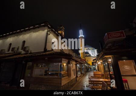 SARAJEVO, BOSNIEN UND HERZEGOWINA - 16. APRIL 2017: Straße mit Touristen und ein Moschee Minarett im Viertel Bascarsija bei Nacht. Bascarsija ist ein Symb Stockfoto