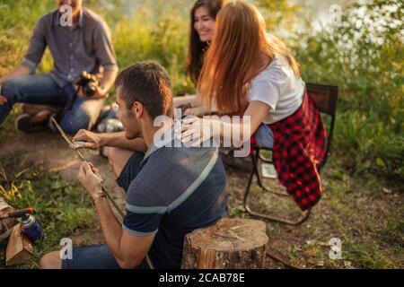 Attraktiver Kerl ist Schneiden Baum Brunch für die Fischerei. Wanderer ist mit einem Messer für die Zubereitung von Lebensmitteln. Seitenansicht Foto Stockfoto