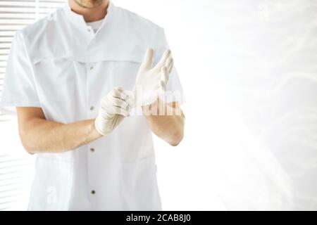 Nahaufnahme beschnittenes Foto. Therapeut trägt Handschuhe im hellen Raum. Stockfoto