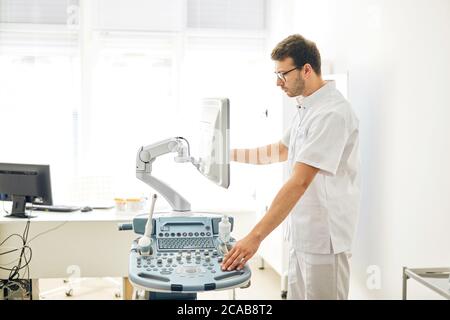 Spezialist steuert die Arbeit des Ultraschallgeräts. Nahaufnahme Seitenansicht Foto. Stockfoto