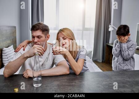 Alkoholiker Eltern kümmern sich nicht um das Kind, kaukasische Familie leiden unter Alkoholabhängigkeit. Verzweifeltes kleines Kind weinen, um Hilfe bitten, braucht etwas lov Stockfoto