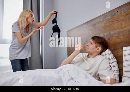 Junge kaukasische Frau fand seltsamen BH zu Hause, Frau fand heraus, über den Verrat ihres Mannes, bleiben Sie in Schock. Mann fast vor Scham verbrannt Stockfoto