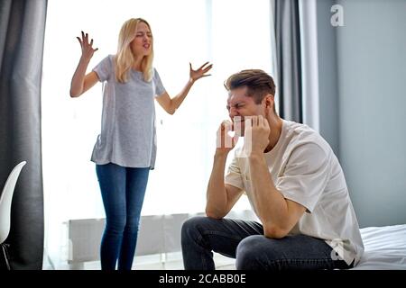 Junge kaukasische Mann 20-25 Jahre alt wollen nicht auf schreiende Frau hören, sie streiten zu Hause, in Hauskleidung, ungesunde Beziehungen, Probleme Stockfoto