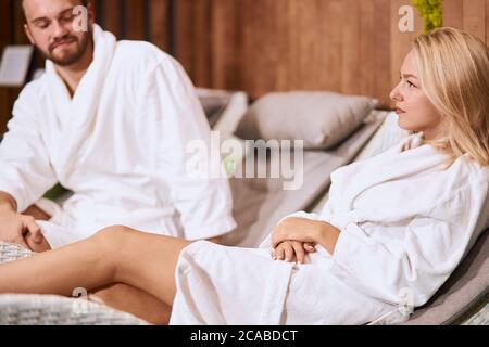 Nahaufnahme der blonden attraktive Frau mit langen geraden Haaren, Blick weg mit selbstbewussten Gesicht, Ausdruck Selbstsicherheit, sitzen in einem komfortablen Ort Stockfoto