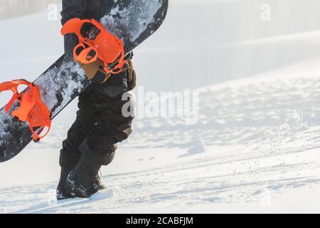 Müdigkeit beim Snowboarden. Müde Kerl hält ein Snowboard und geht nach oben. Seitenansicht abgeschnitten Foto. Copy space Stockfoto