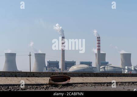 Schornsteine eines Kraftwerks, die Rauch in den blauen Himmel ausstrahlen. Stockfoto