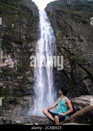CANASTRA, BRASILIEN - 14. Jul 2020: Boy schaut erstaunt auf riesigen und wunderschönen Wasserfall in Serra da Canastra, Brasilien, genannt Casca Danta. Stockfoto