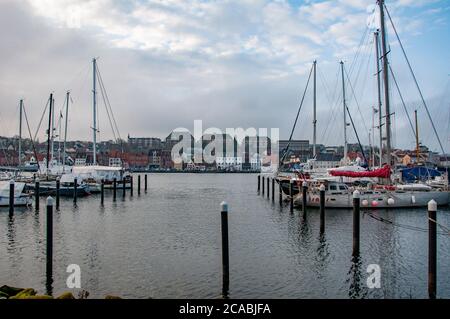 FLENSBURG, DEUTSCHLAND. JANUAR 2020. Yachts an der Anlegestelle Menschen, die auf dem Böschung spazieren gehen Stockfoto