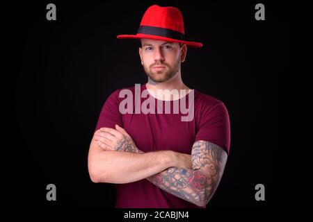 Schöner bärtiger Mann mit Hut vor schwarzem Hintergrund Stockfoto