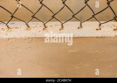 Nahaufnahme alten Eisendraht Zaun Vintage-Netz auf dem Hintergrund der Beton beige gemalten Wand. Kopierraum ideal für die Verwendung im Design oder Tapete Stockfoto