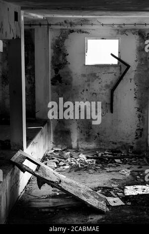 Schwarz und weiß von geplünderten Zimmer, zerstörte Tür und Fenster und Schutt auf dem Boden. Verlassene Gebäude am Monte Grappa (Venetien, Italien) Stockfoto