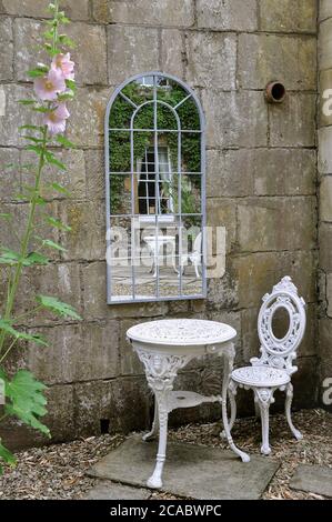 Ein englischer Garten im Innenhof mit einem weißen schmiedeeisernen Tisch und Stuhl vor einem Fenster im georgianischen Stil Stockfoto