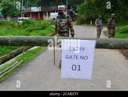 Das Personal des TSR (Tripura State Gewehre) patrouilliert den Bereich vor einem provisorischen Tor in einer Eindämmungszone, um die Ausbreitung des Coronavirus am Stadtrand von Agartala zu verhindern. Tripura, Indien. Stockfoto