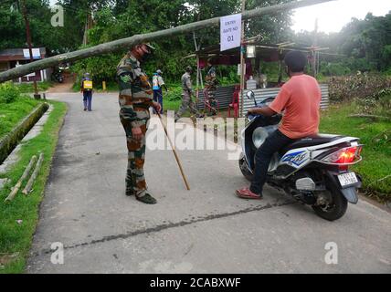 Das Personal des TSR (Tripura State Gewehre) patrouilliert den Bereich vor einem provisorischen Tor in einer Eindämmungszone, um die Ausbreitung des Coronavirus am Stadtrand von Agartala zu verhindern. Tripura, Indien. Stockfoto