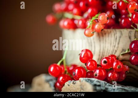 Frische rote Johannisbeeren auf dem Teller auf einem rustikalen Holztisch. Hintergrund mit Kopierbereich. Selektiver Fokus. Stockfoto