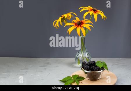 rudbeckia blüht in einer transparenten Vase auf einem grauen Betontisch Stockfoto