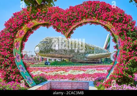 DUBAI, VAE - 5. MÄRZ 2020: Der herzförmige Bogen mit Petunien vor Emirates A380, bedeckt mit weißen Blumen und grünem Logo, Miracle Stockfoto