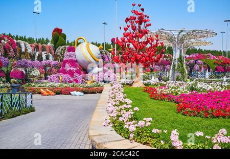 DUBAI, VAE - 5. MÄRZ 2020: Spazieren Sie durch die Miracle Garden Gasse und genießen Sie die landschaftlichen Dekorationen - Liebe Baum mit hängenden Herzen, riesigen Sonnenschirmen und Teekanne Stockfoto