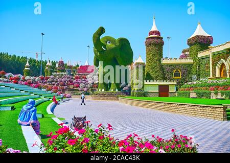 DUBAI, VAE - 5. MÄRZ 2020: Das Amphitheater des Miracle Garden mit farbigen Blumenbeeten, Schloss hinter der Bühne und den Installationen von Elefanten, Co Stockfoto