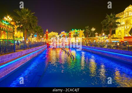 DUBAI, VAE - 5. MÄRZ 2020: Der Kanal des Global Village ist mit hellen Lichtern an den Ufern, Brunnen und malerischen Fußgängerbrücken geschmückt Stockfoto