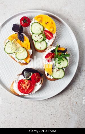 Verschiedene Sandwiches mit Frischkäse, Tomaten, Gurken, Basilikum, Rucola und Zitrone. Stockfoto