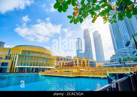 DUBAI, VAE - 3. MÄRZ 2020: Die schattige Promenade des Burj Khalifa Sees mit Blick auf die Al Bahar Brücke und große Dubai Mall mit Wolkenkratzern im Hintergrund, Stockfoto