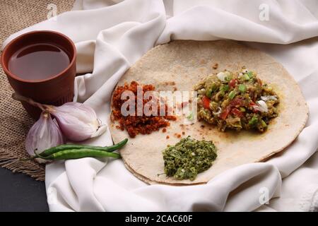 Baigan/Baingan Bharta - geröstete Aubergine mit Gewürzen und Gemüse, zerdrückte gree Chilis - Thecha und Knoblauch Chutney. Mit Jowar Brot Stockfoto