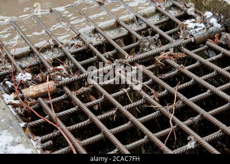 Eisenrost zum Ablassen von Wasser in der Stadt. Alter Abflussgraben. Stockfoto