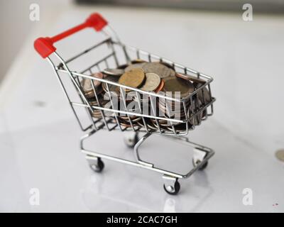 Mini-Modell Cart Typ im Supermarkt und viele Münzen Hintergrund aus Fokus Hintergrund Stockfoto