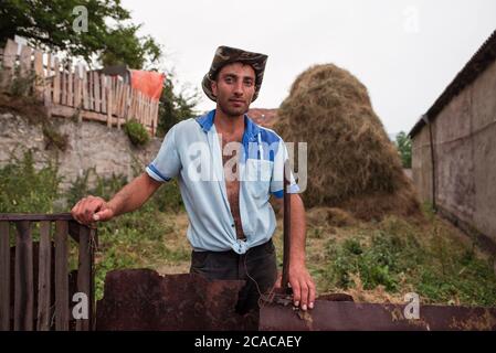 Alaverdi / Armenien - 20. Juli 2019: Porträt eines attraktiven armenischen jungen Mannes, der in der Landwirtschaft mit einer Gabel arbeitet Stockfoto