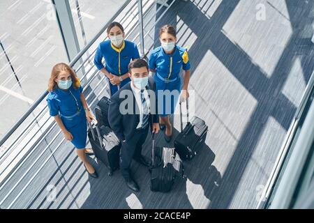 Vier Flugbegleiter in Masken schauen nach oben Stockfoto