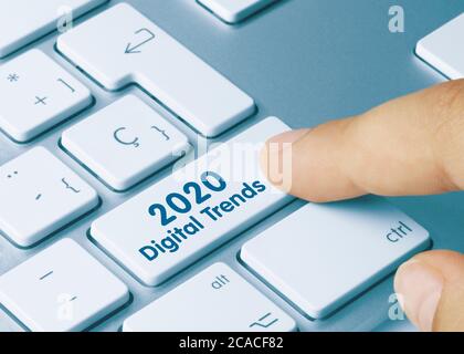 2020 Digitale Trends geschrieben auf White Key der metallischen Tastatur. Drücken Sie die Taste mit dem Finger Stockfoto