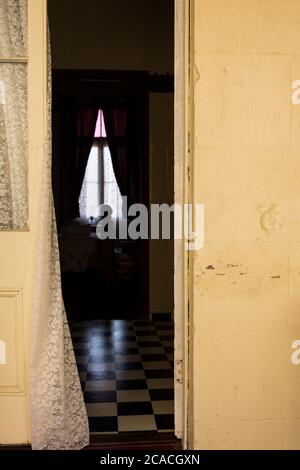 Vorhang, der in die offene Tür zu einem Schlafzimmer in einem alten Haus im Queenslander Stil mit französischen Türen weht Stockfoto