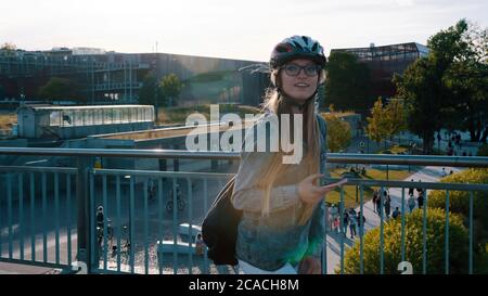 Porträt einer jungen glücklichen Frau, die über die Brücke und mit einem Smartphone Schlittschuh. . Hochwertige Fotos Stockfoto