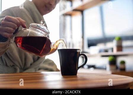 Frau, die sich eine Tasse schwarzen Tee serviert Stockfoto