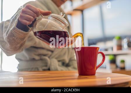 Frau, die sich eine Tasse schwarzen Tee serviert Stockfoto