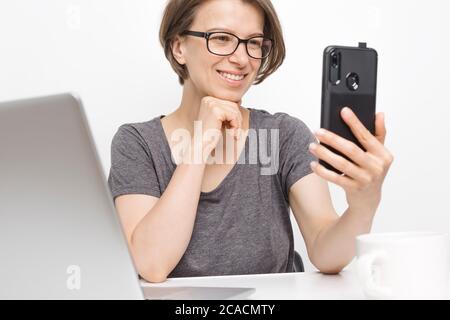 Eine Bloggerin hält ein Smartphone in der Hand und bereitet sich auf eine Online-Konferenz vor. Stockfoto