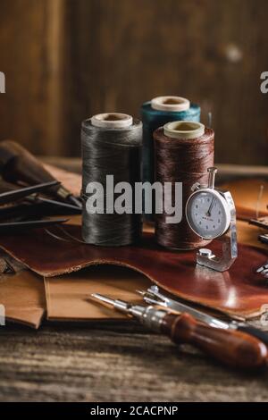 Leder Handwerk Werkzeuge auf alten Holztisch. Lederwerkstatt. Stockfoto