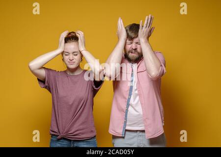 Mann und Frau leiden unter Kopfschmerzen, sie halten den Kopf mit den Händen und schließen die Augen. Gesundheitskonzept. Stockfoto