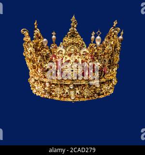 Goldene Krone mit Edelsteinen isoliert auf dunkelblauem Hintergrund Stockfoto